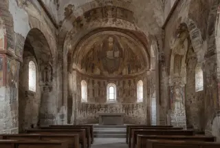 Intérieur de l’église Saint-Martin de Vic montrant ses fresques romanes médiévales aux tons ocres autour du chœur et de l’abside.